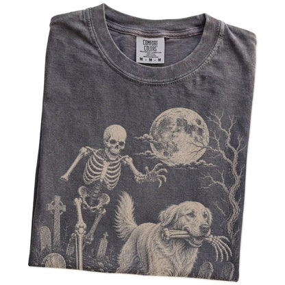 Folded Pepper Comfort Colors® T-shirt showing Golden Retriever running through a moonlit graveyard with a chasing skeleton