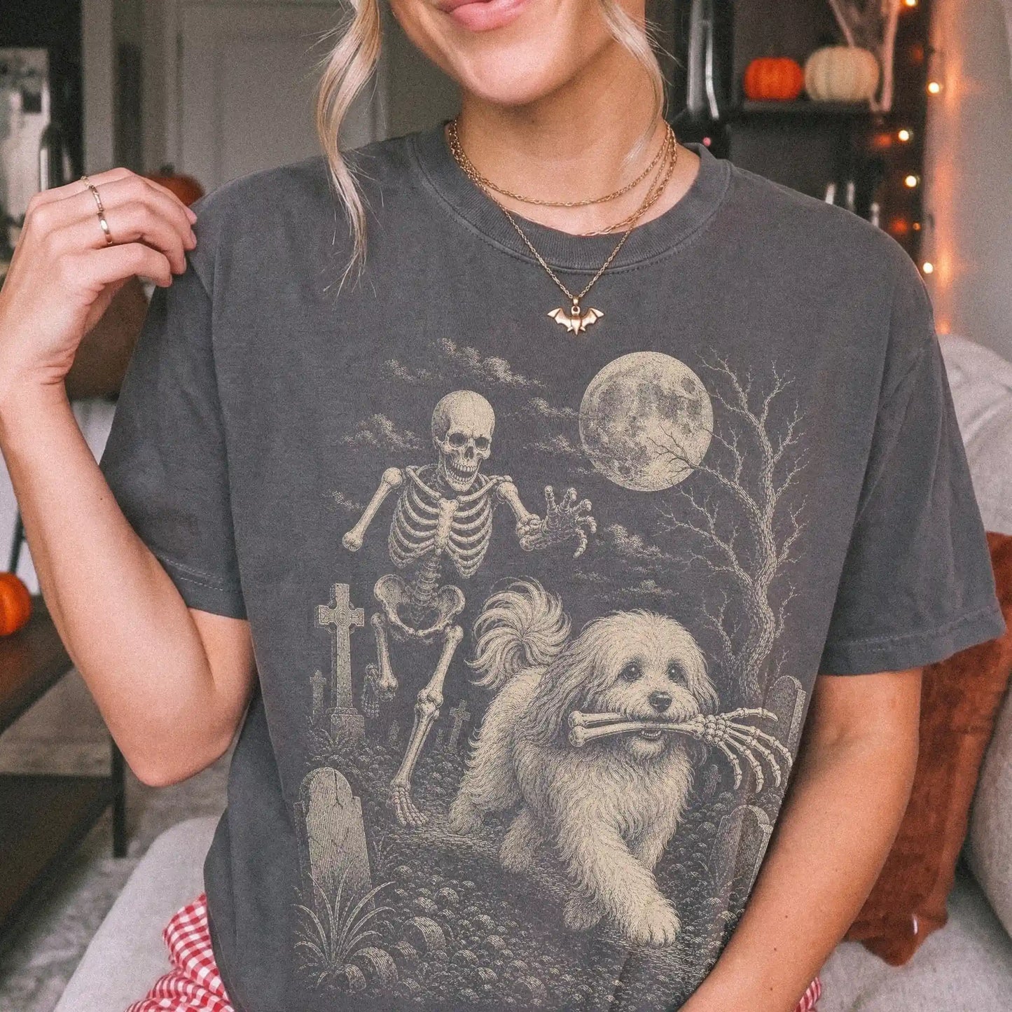 Model wearing a Pepper Comfort Colors® T-shirt showing Havanese running through a moonlit graveyard with a chasing skeleton