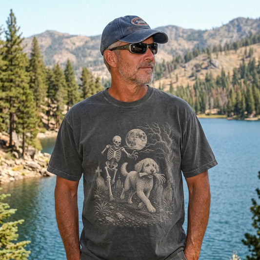 Model wearing a Pepper Comfort Colors® T-shirt showing Labradoodle running through a moonlit graveyard with a chasing skeleto