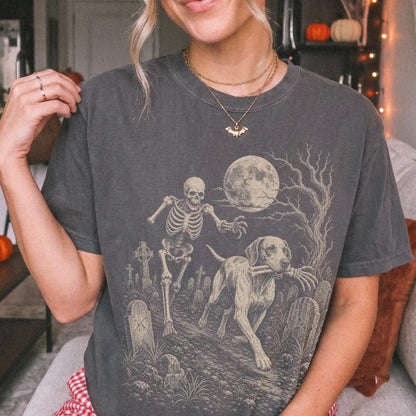 Model wearing a Pepper Comfort Colors® T-shirt showing Pointer running through a moonlit graveyard with a chasing skeleton