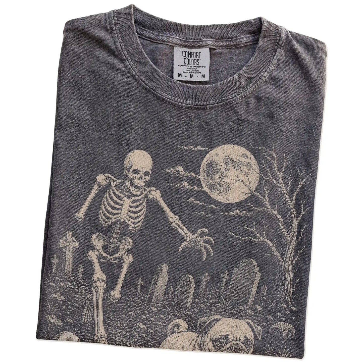 Folded Pepper Comfort Colors® T-shirt showing Pug running through a moonlit graveyard with a chasing skeleton