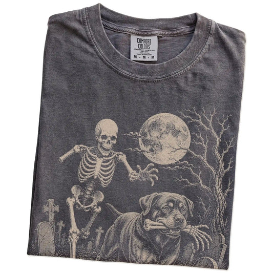 Folded Pepper Comfort Colors® T-shirt showing Rottweiler running through a moonlit graveyard with a chasing skeleton