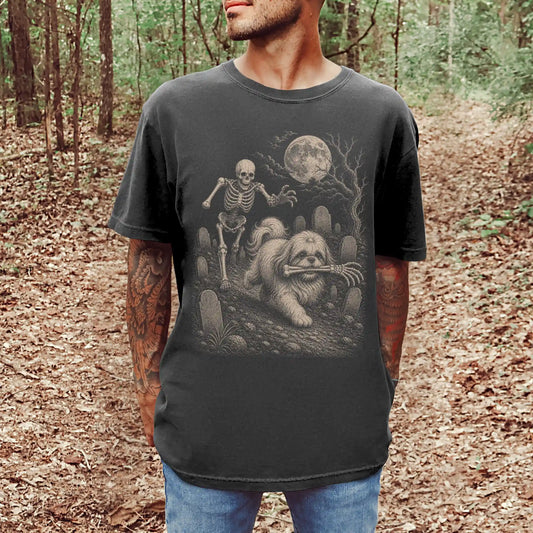 Model wearing a Pepper Comfort Colors® T-shirt showing Shih Tzu running through a moonlit graveyard with a chasing skeleton