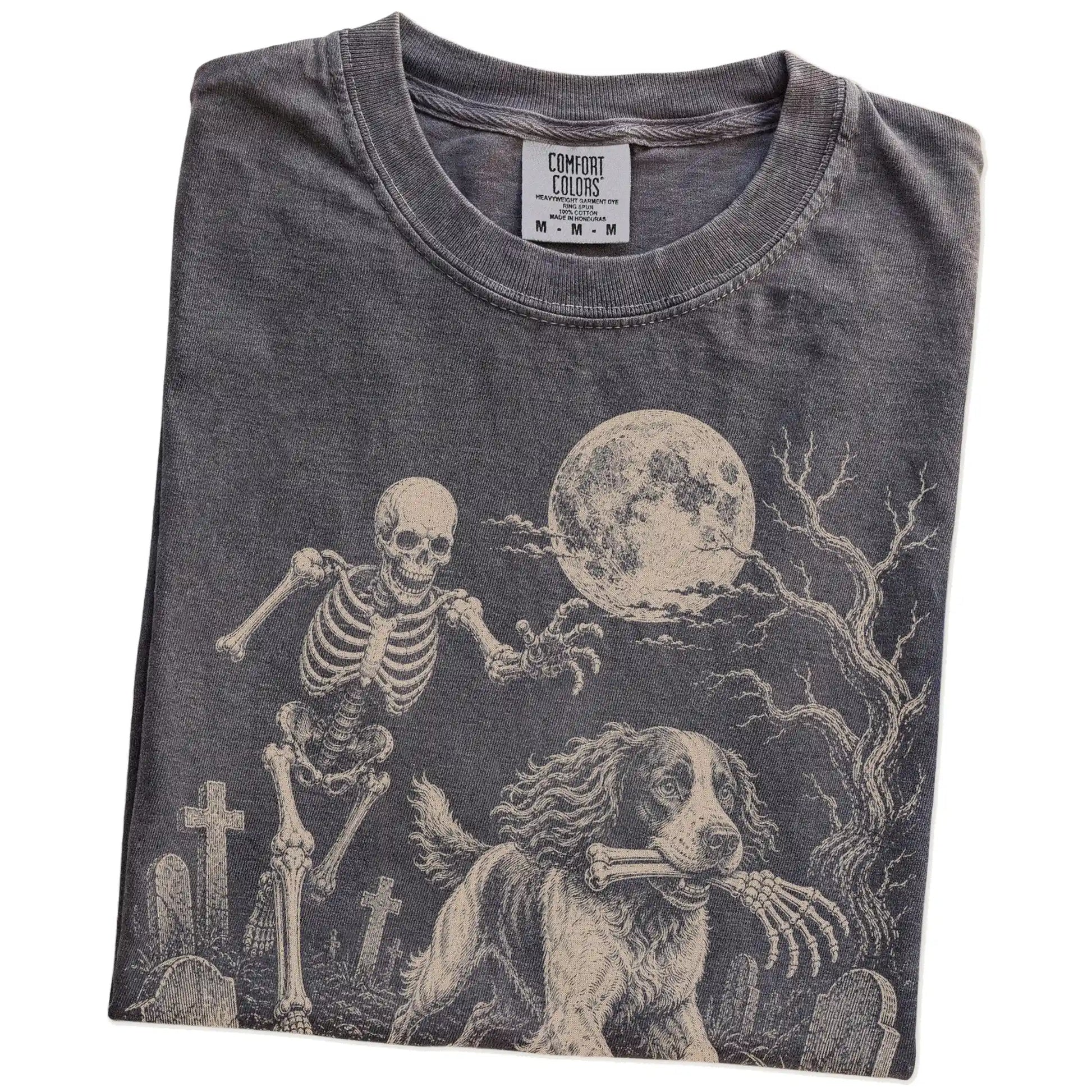 Folded Pepper Comfort Colors® T-shirt showing Springer Spaniel running through a moonlit graveyard with a chasing skeleton