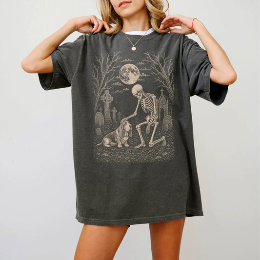 Model wearing a Pepper Comfort Colors® T-shirt showing Basset Hound sharing a quiet cemetery moment with a friendly skeleton