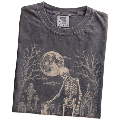Folded Pepper Comfort Colors® T-shirt showing Belgian Malinois sharing a quiet cemetery moment with a friendly skeleton