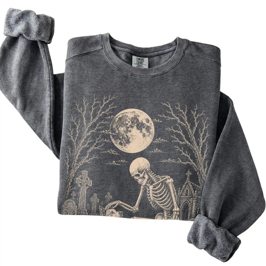 Folded Pepper sweatshirt with a skeleton petting a Blue Heeler in a graveyard