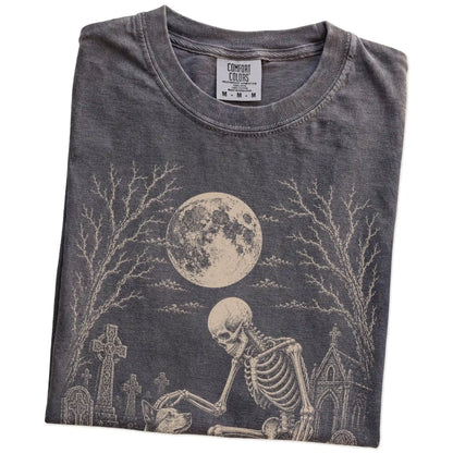 Folded Pepper Comfort Colors® T-shirt showing Blue Heeler sharing a quiet cemetery moment with a friendly skeleton