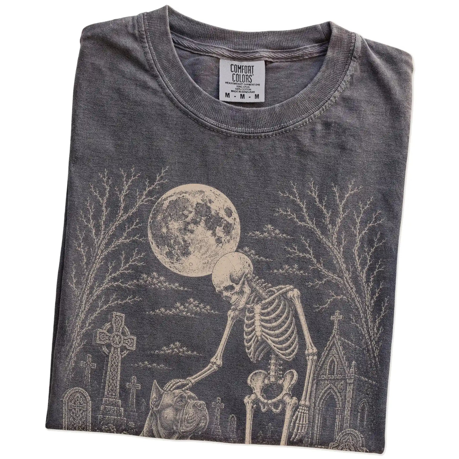 Folded Pepper Comfort Colors® T-shirt showing Cane Corso sharing a quiet cemetery moment with a friendly skeleton