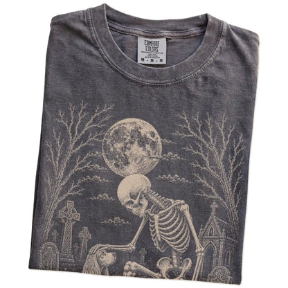 Folded Pepper Comfort Colors® T-shirt showing Cocker Spaniel sharing a quiet cemetery moment with a friendly skeleton