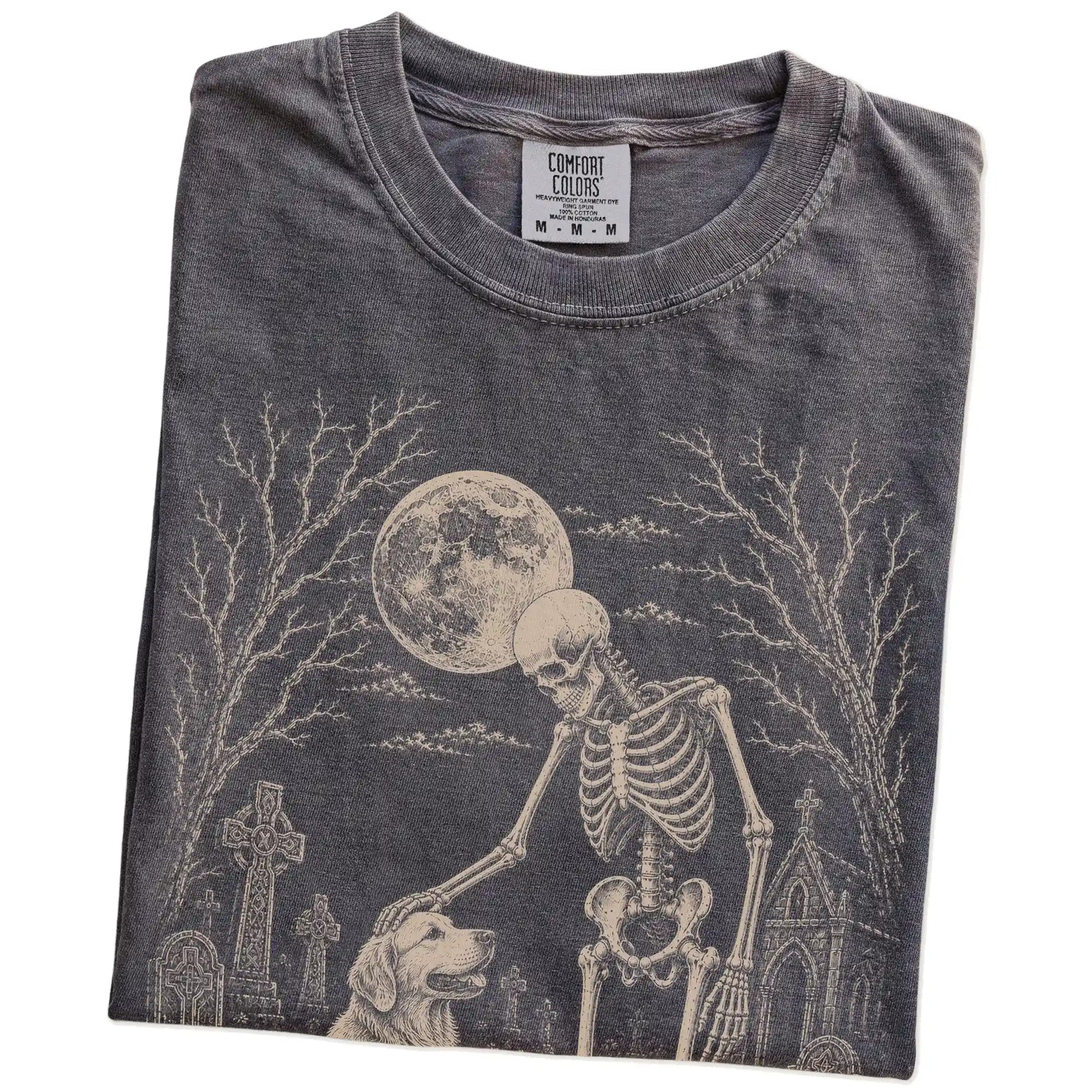 Folded Pepper Comfort Colors® T-shirt showing Golden Retriever sharing a quiet cemetery moment with a friendly skeleton