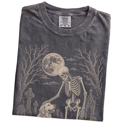 Folded Pepper Comfort Colors® T-shirt showing Golden Retriever sharing a quiet cemetery moment with a friendly skeleton