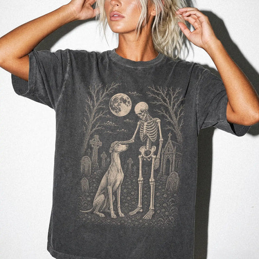 Model wearing a Pepper Comfort Colors® T-shirt showing Greyhound sharing a quiet cemetery moment with a friendly skeleton