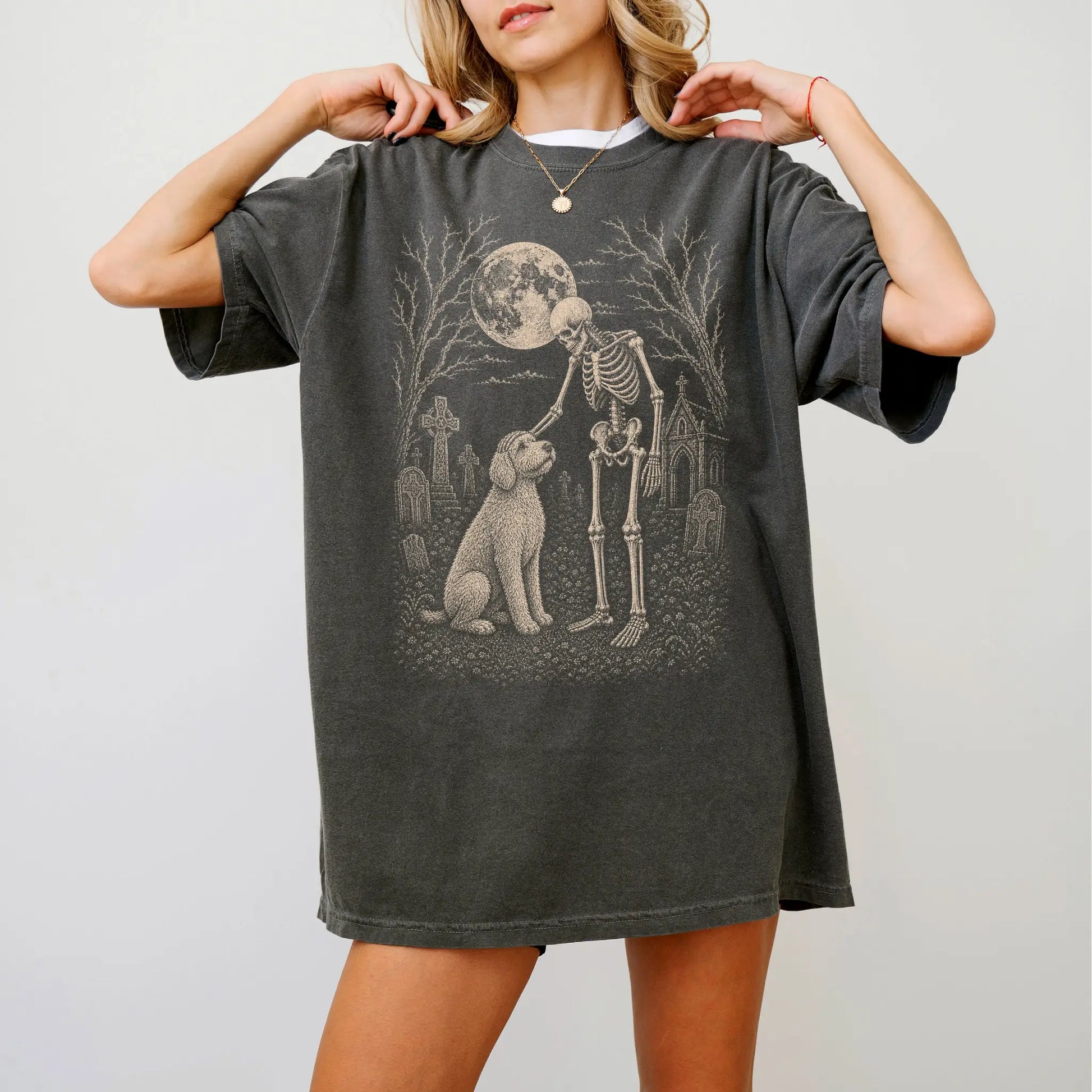 Model wearing a Pepper Comfort Colors® T-shirt showing Labradoodle sharing a quiet cemetery moment with a friendly skeleton