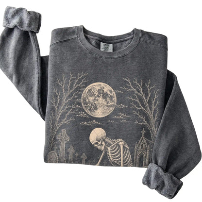 Folded Pepper sweatshirt with a skeleton petting a Maltese in a graveyard