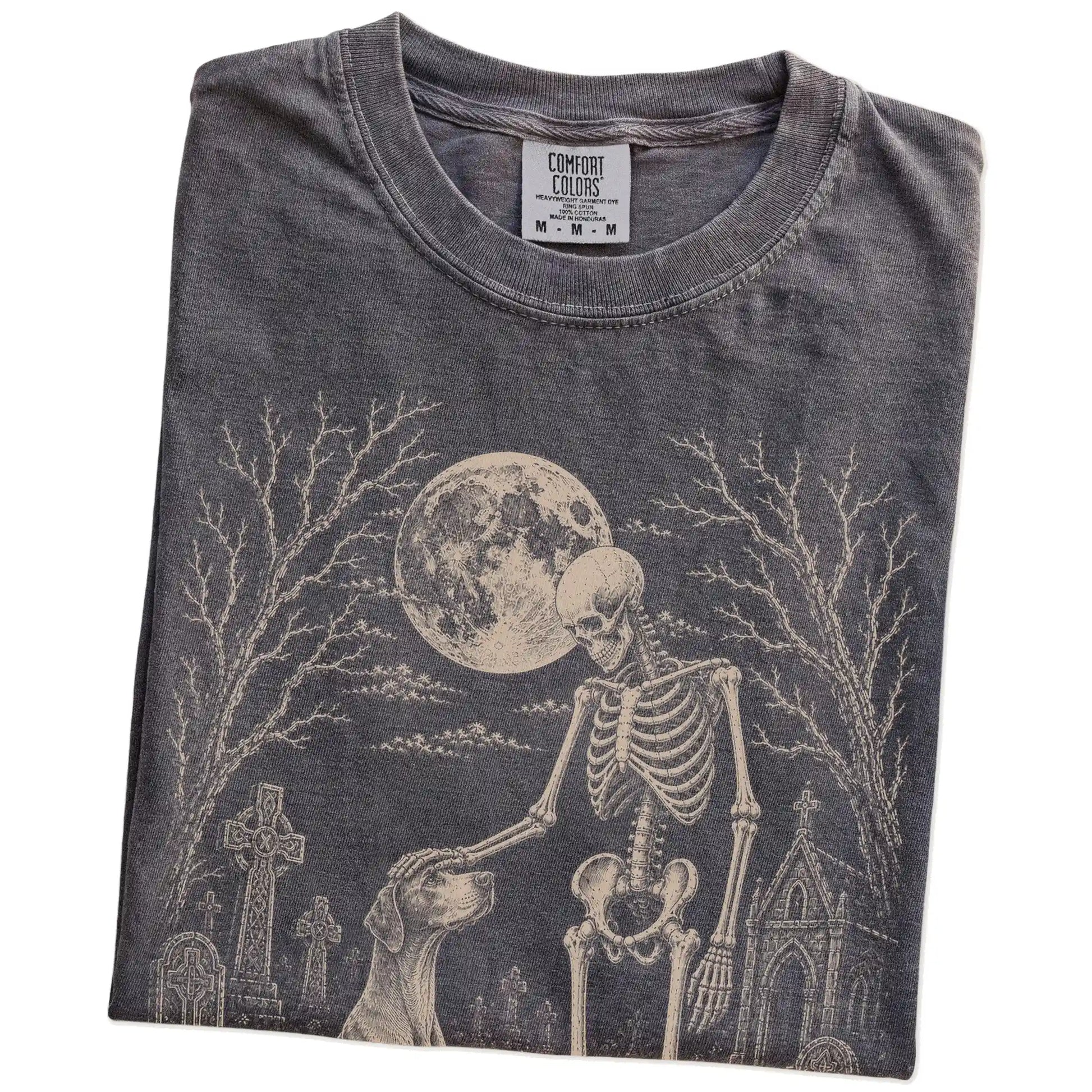 Folded Pepper Comfort Colors® T-shirt showing Pointer sharing a quiet cemetery moment with a friendly skeleton