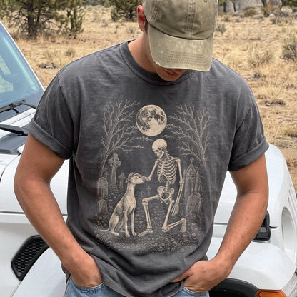 Model wearing a Pepper Comfort Colors® T-shirt showing Whippet sharing a quiet cemetery moment with a friendly skeleton