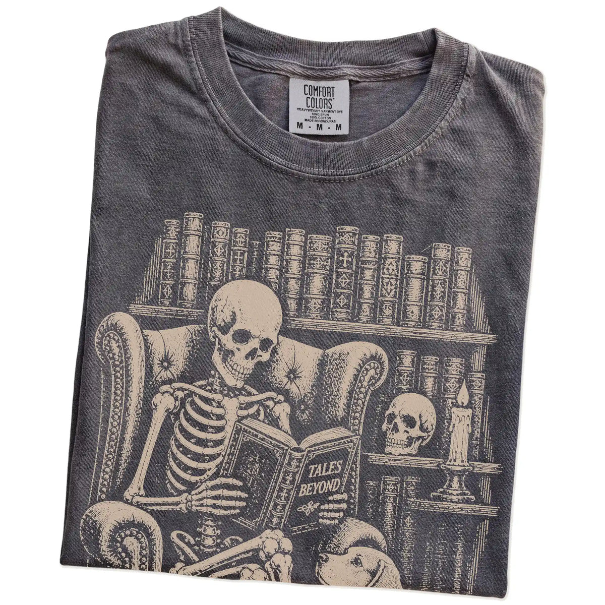 Folded Pepper Comfort Colors® T-shirt showing skeleton reading in a library beside a Beagle