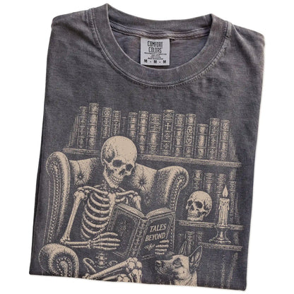 Folded Pepper Comfort Colors® T-shirt showing skeleton reading in a library beside a Belgian Malinois