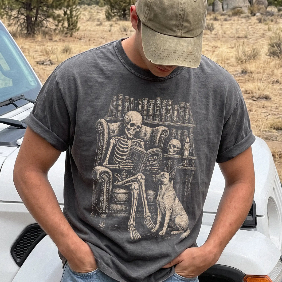 Model wearing a Pepper Comfort Colors® T-shirt showing skeleton reading in a library beside a Belgian Malinois