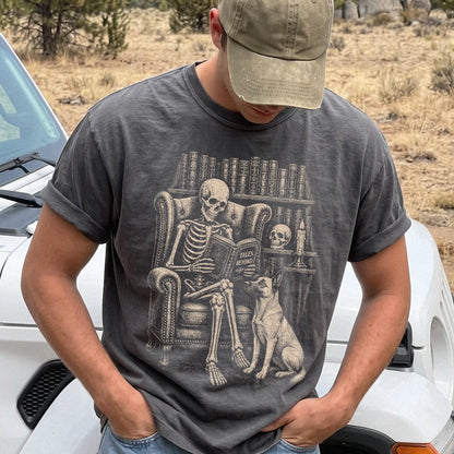 Model wearing a Pepper Comfort Colors® T-shirt showing skeleton reading in a library beside a Belgian Malinois
