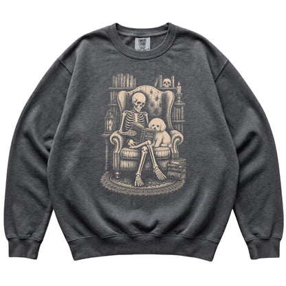 Skeleton reading Tales Beyond to a Bichon Frise on a Pepper sweatshirt