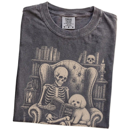 Folded Pepper Comfort Colors® T-shirt showing skeleton reading in a library beside a Bichon Frise