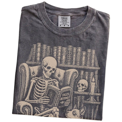 Folded Pepper Comfort Colors® T-shirt showing skeleton reading in a library beside a Blue Heeler