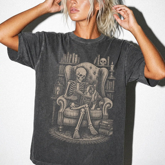 Model wearing a Pepper Comfort Colors® T-shirt showing skeleton reading in a library beside a Boston Terrier