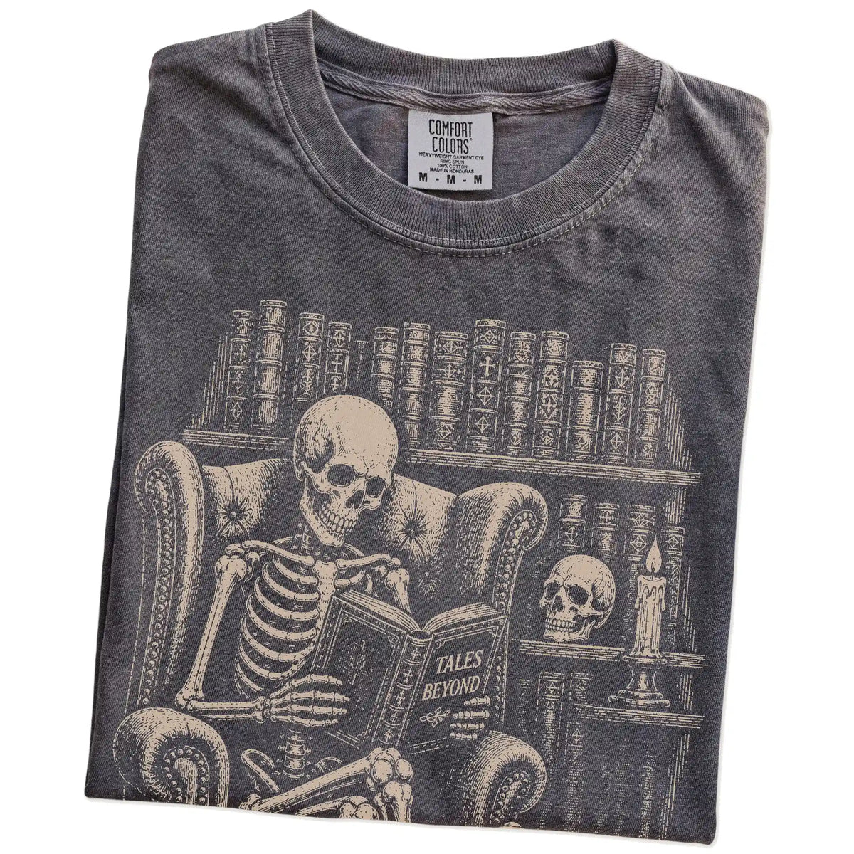 Folded Pepper Comfort Colors® T-shirt showing skeleton reading in a library beside a Bulldog