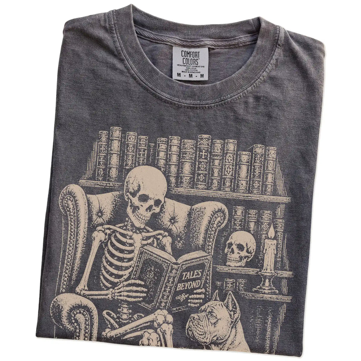 Folded Pepper Comfort Colors® T-shirt showing skeleton reading in a library beside a Cane Corso