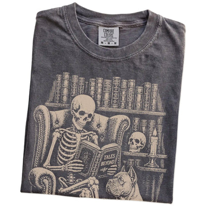 Folded Pepper Comfort Colors® T-shirt showing skeleton reading in a library beside a Cane Corso
