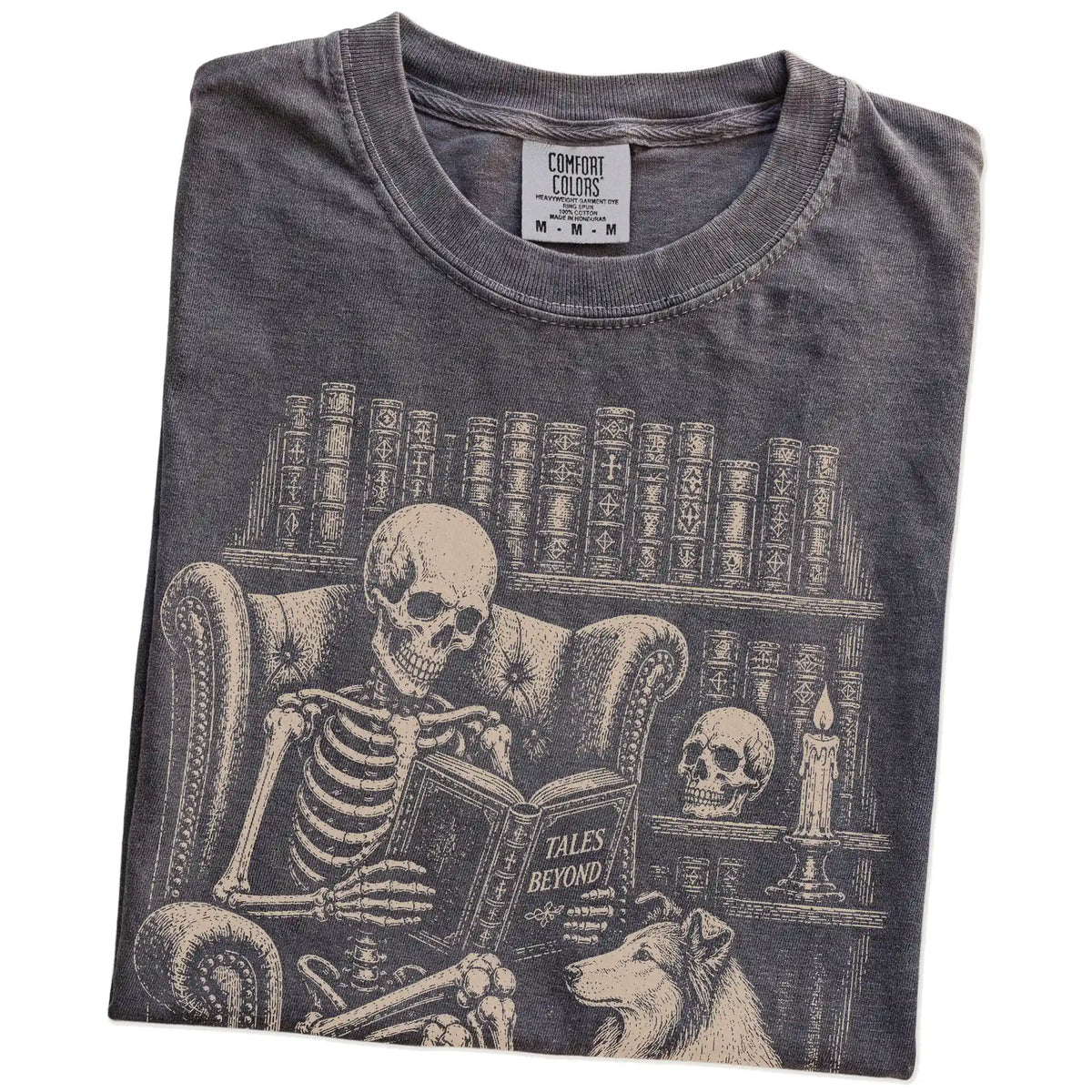 Folded Pepper Comfort Colors® T-shirt showing skeleton reading in a library beside a Collie