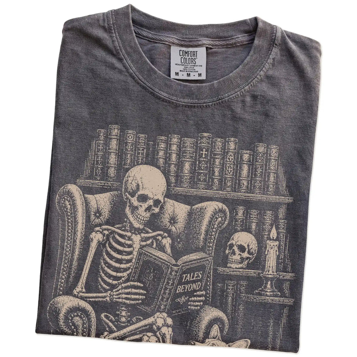 Folded Pepper Comfort Colors® T-shirt showing skeleton reading in a library beside a Corgi