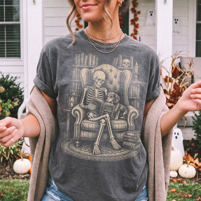 Model wearing a Pepper Comfort Colors® T-shirt showing skeleton reading in a library beside a Dachshund