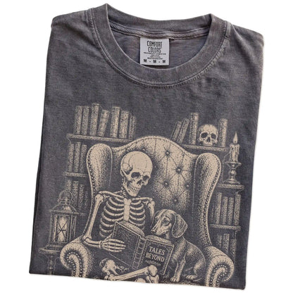 Folded Pepper Comfort Colors® T-shirt showing skeleton reading in a library beside a Dachshund