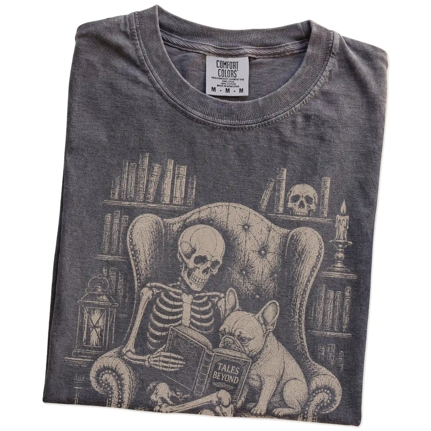 Folded Pepper Comfort Colors® T-shirt showing skeleton reading in a library beside a French Bulldog
