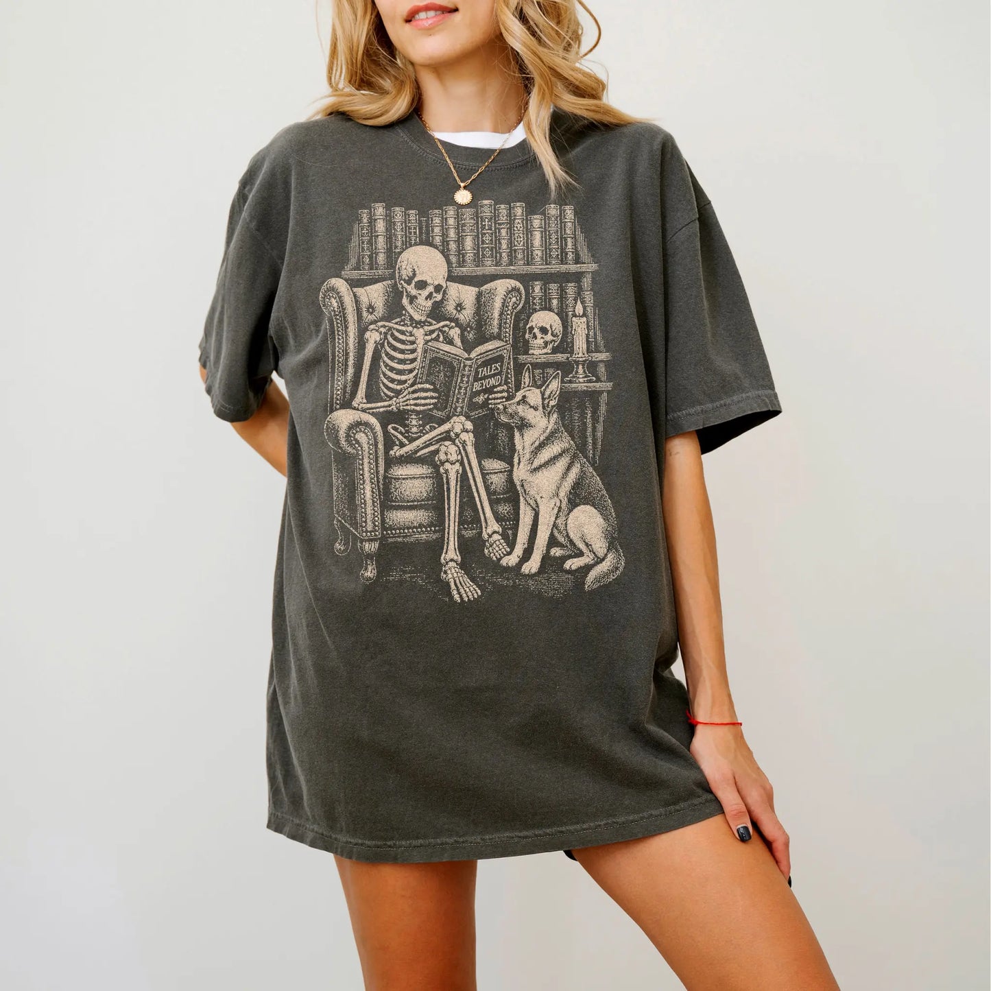 Model wearing a Pepper Comfort Colors® T-shirt showing skeleton reading in a library beside a German Shepherd