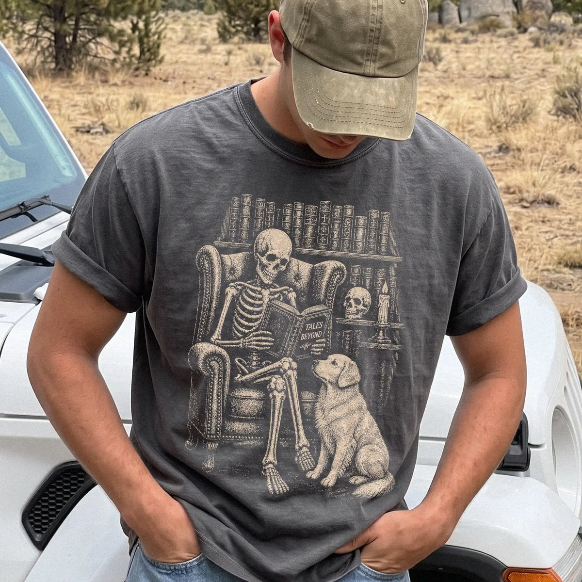 Model wearing a Pepper Comfort Colors® T-shirt showing skeleton reading in a library beside a Golden Retriever