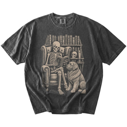 Skeleton reading in a library beside a Newfie on a Pepper Comfort Colors® T-shirt