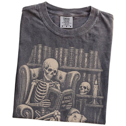 Folded Pepper Comfort Colors® T-shirt showing skeleton reading in a library beside a Pitbull