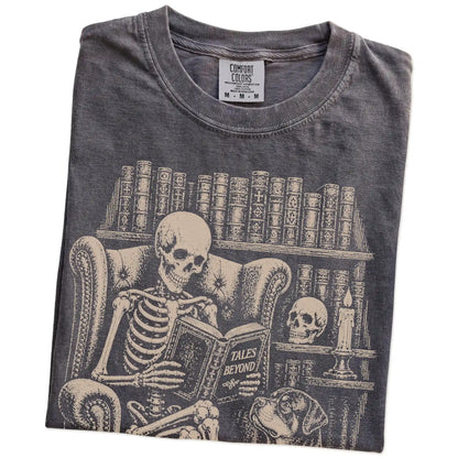 Folded Pepper Comfort Colors® T-shirt showing skeleton reading in a library beside a Rottweiler