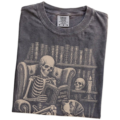 Folded Pepper Comfort Colors® T-shirt showing skeleton reading in a library beside a Saint Bernard