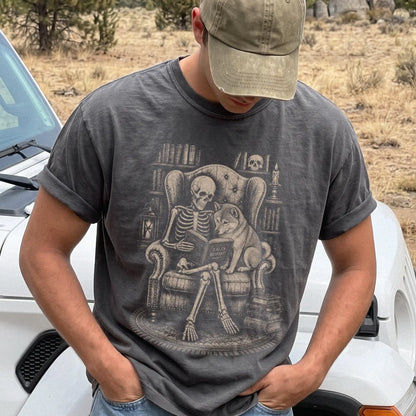Model wearing a Pepper Comfort Colors® T-shirt showing skeleton reading in a library beside a Shiba Inu