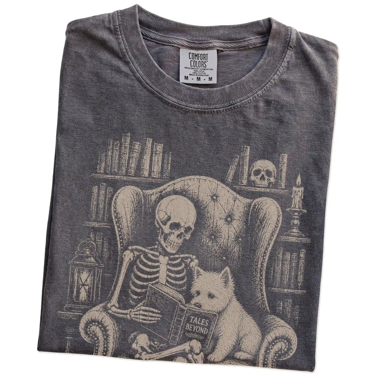 Folded Pepper Comfort Colors® T-shirt showing skeleton reading in a library beside a Westie