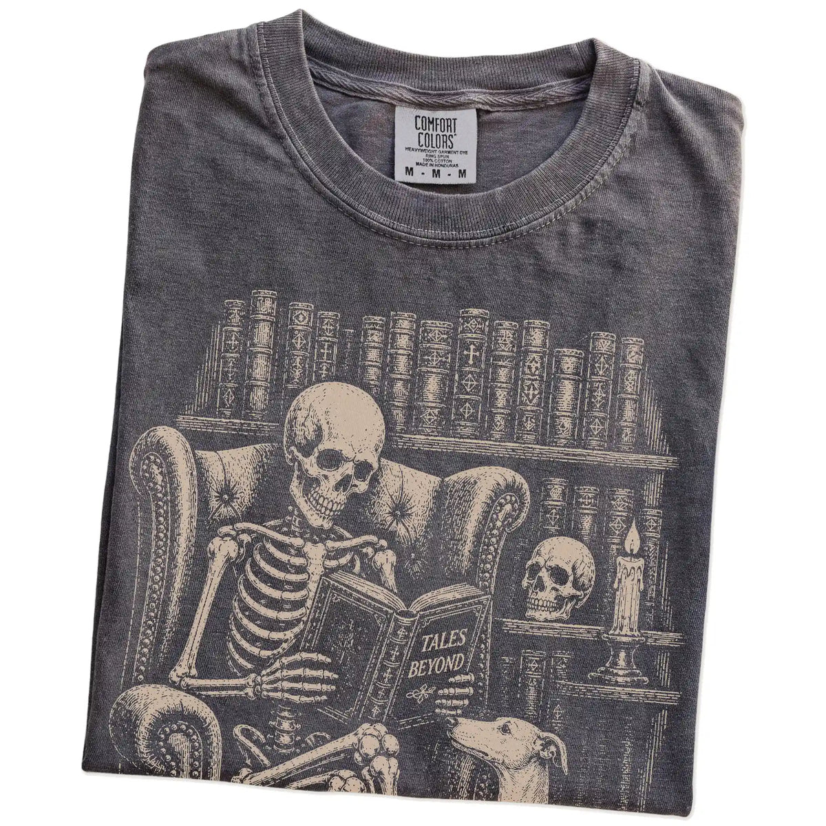 Folded Pepper Comfort Colors® T-shirt showing skeleton reading in a library beside a Whippet