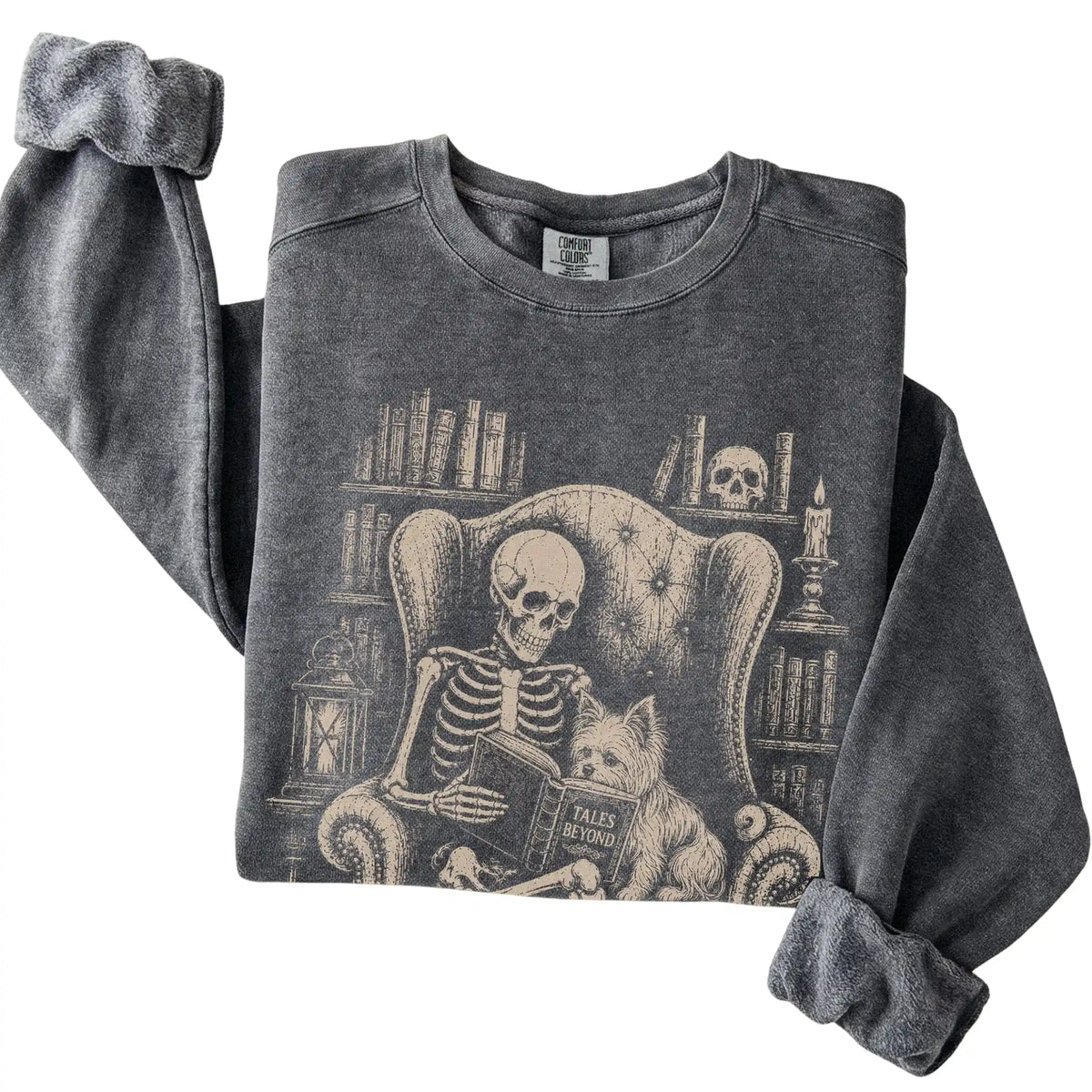 Folded Pepper sweatshirt with a skeleton reading Tales Beyond to a Yorkie
