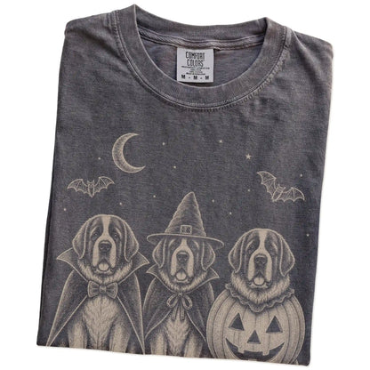 Folded Pepper Comfort Colors® T-shirt showing three St Bernard dogs dressed for Halloween beneath bats and a crescent moon