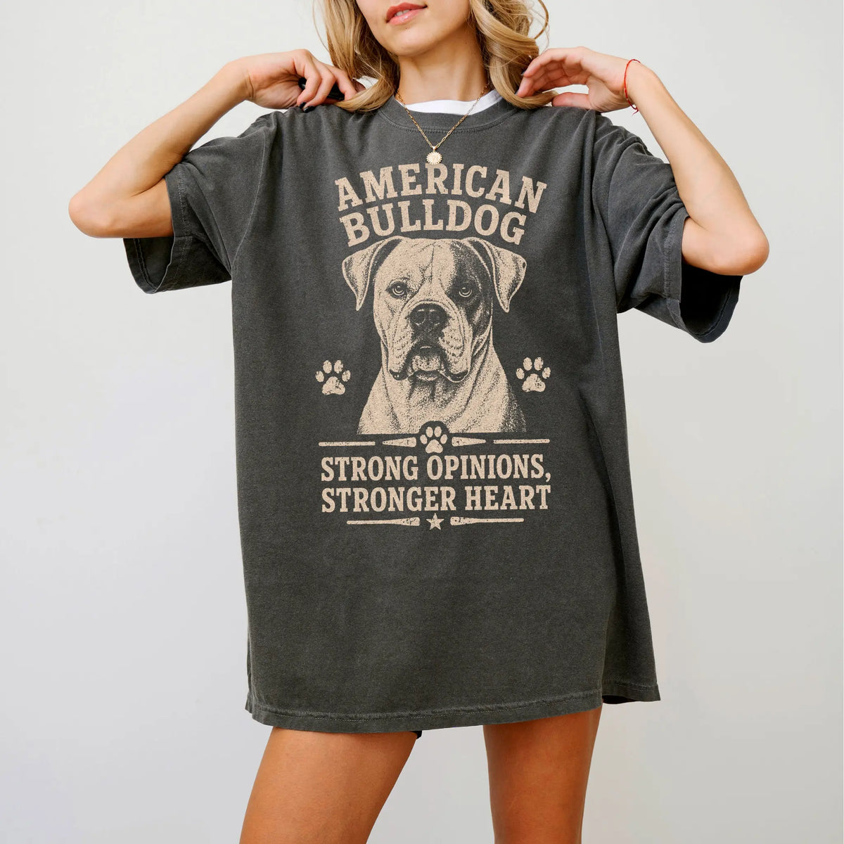 Model wearing a Pepper Comfort Colors® T-shirt featuring American Bulldog design with “Strong Opinions, Stronger Heart” lette