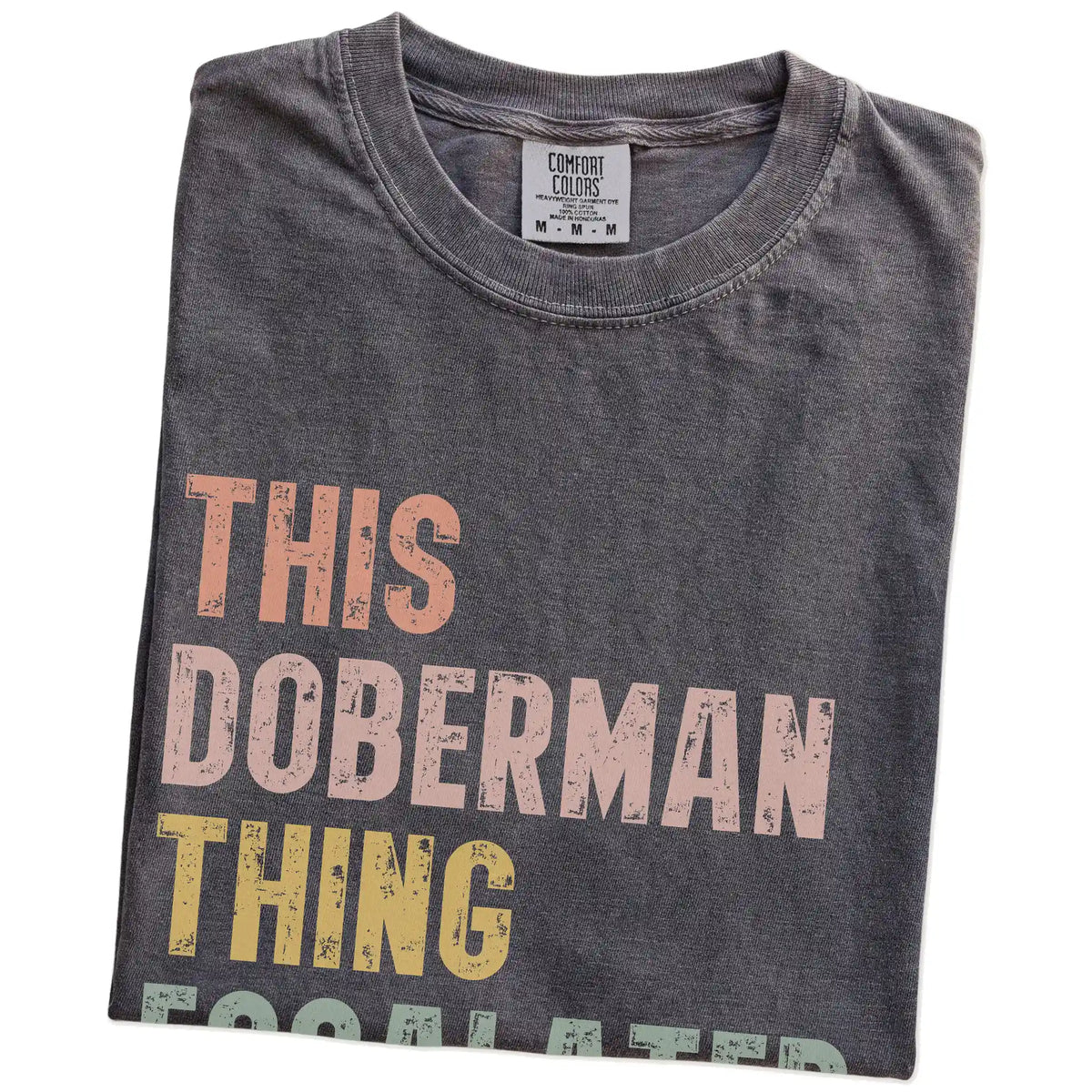 Folded Pepper Comfort Colors® T-shirt showing retro “This Doberman Thing Escalated Quickly” lettering